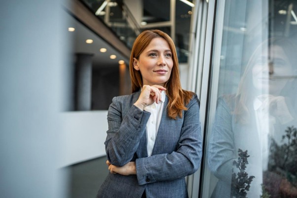 A woman reflecting beside an office window